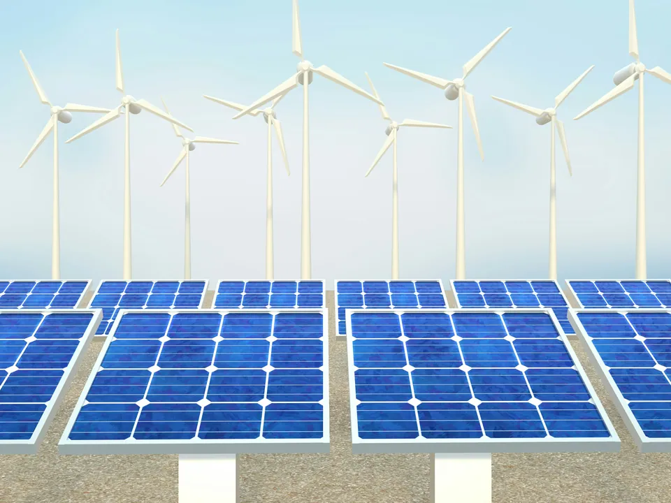 Solar panels in front of a row of wind turbines