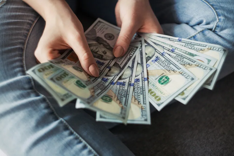 Hands fanning out a stack of hundred-dollar bills