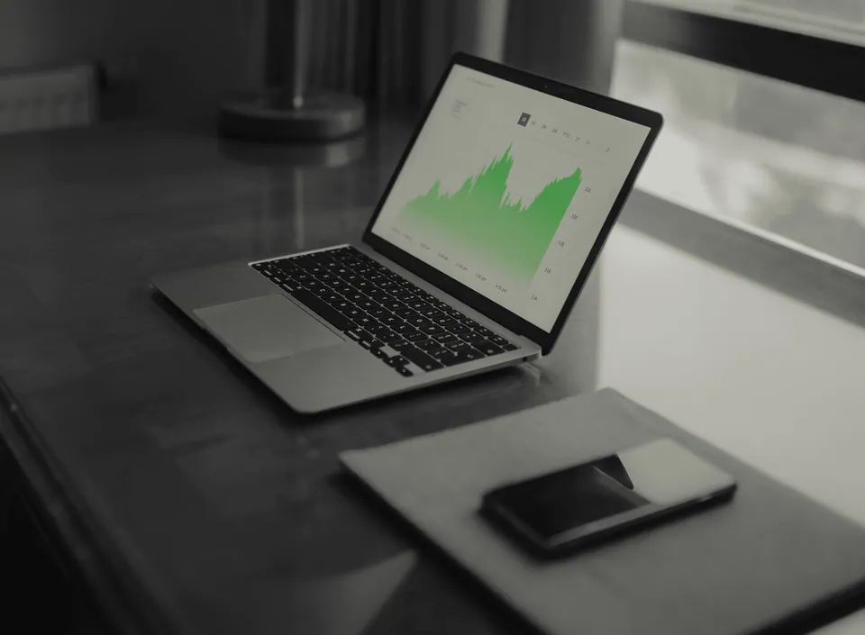 Laptop showing a green area chart on a dark desk