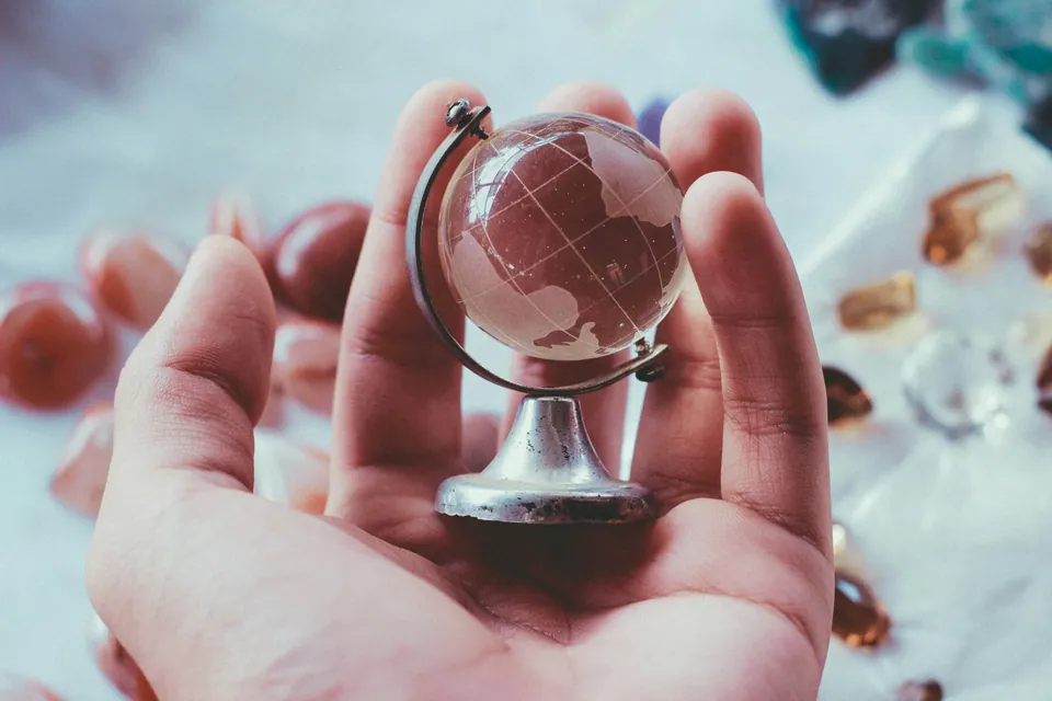 Hand holding a small rose-gold globe