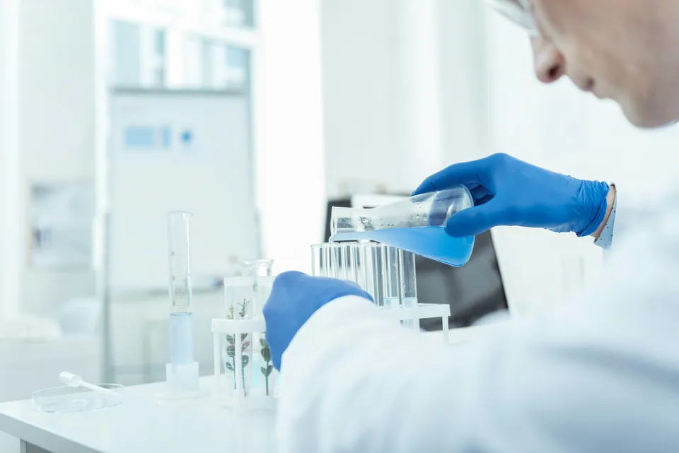 Lab scientist pouring blue liquid into test tubes