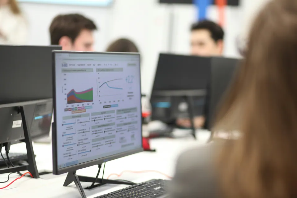 Monitor showing financial charts in a busy office