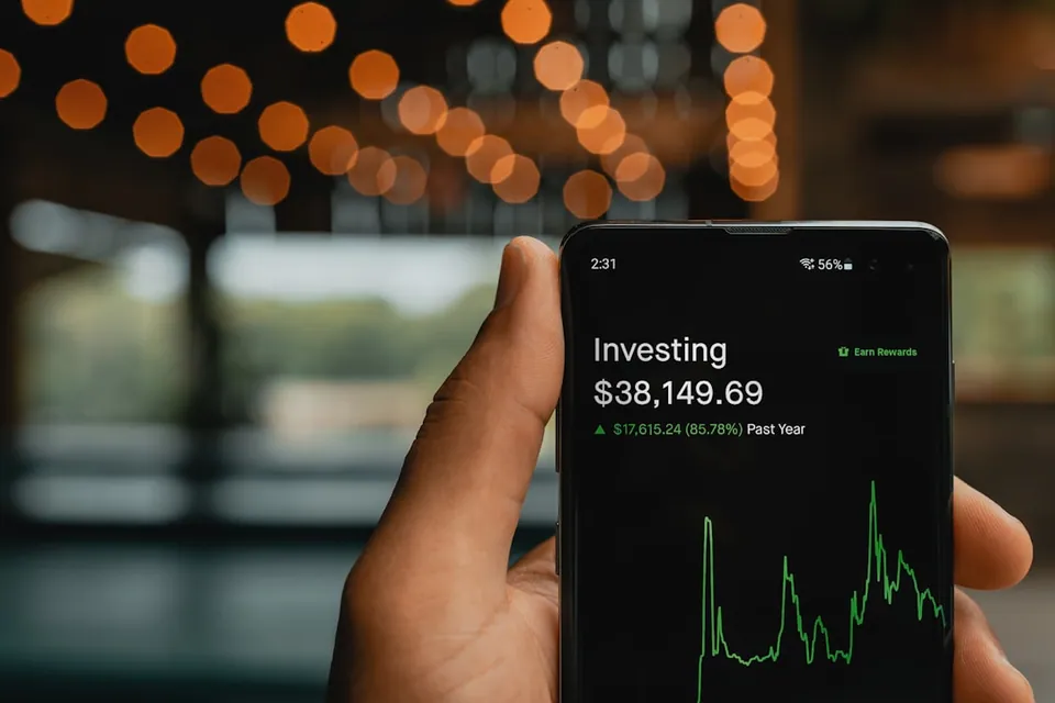Hand holding a phone showing an investing balance of $38,149.69