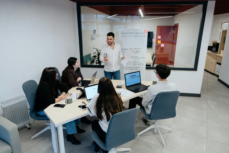 Presenter leading a team meeting in a glass-walled conference room