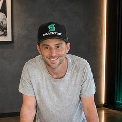 Jordan Rothstein in a Smacktok cap, leaning on a table of graded vintage baseball cards