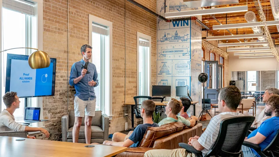 Speaker presenting to a team in a brick-walled startup office