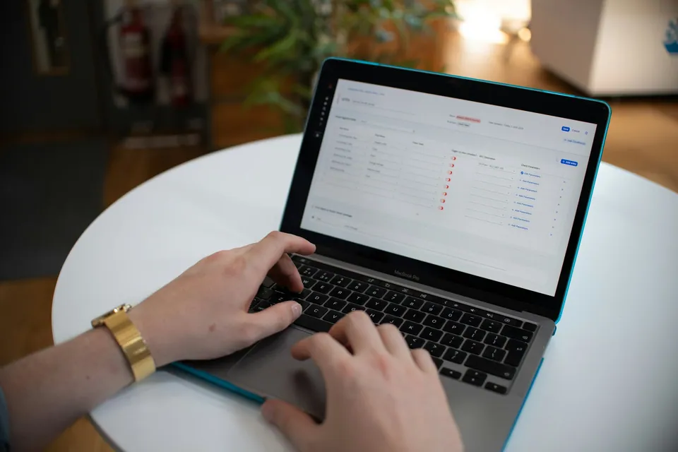 Hands typing on a laptop showing a portfolio spreadsheet