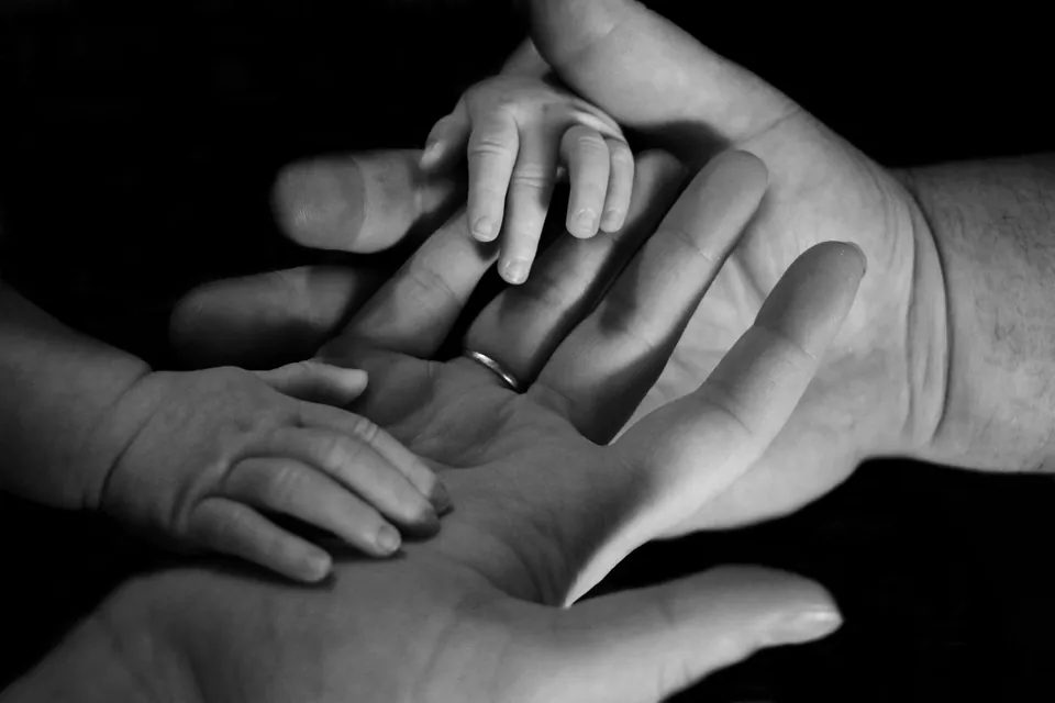 Black and white photo of a baby hand in adult hands