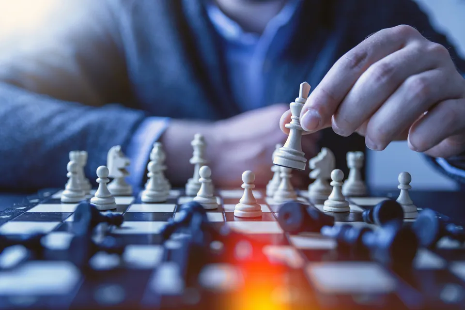 Hand moving a white chess piece across a board