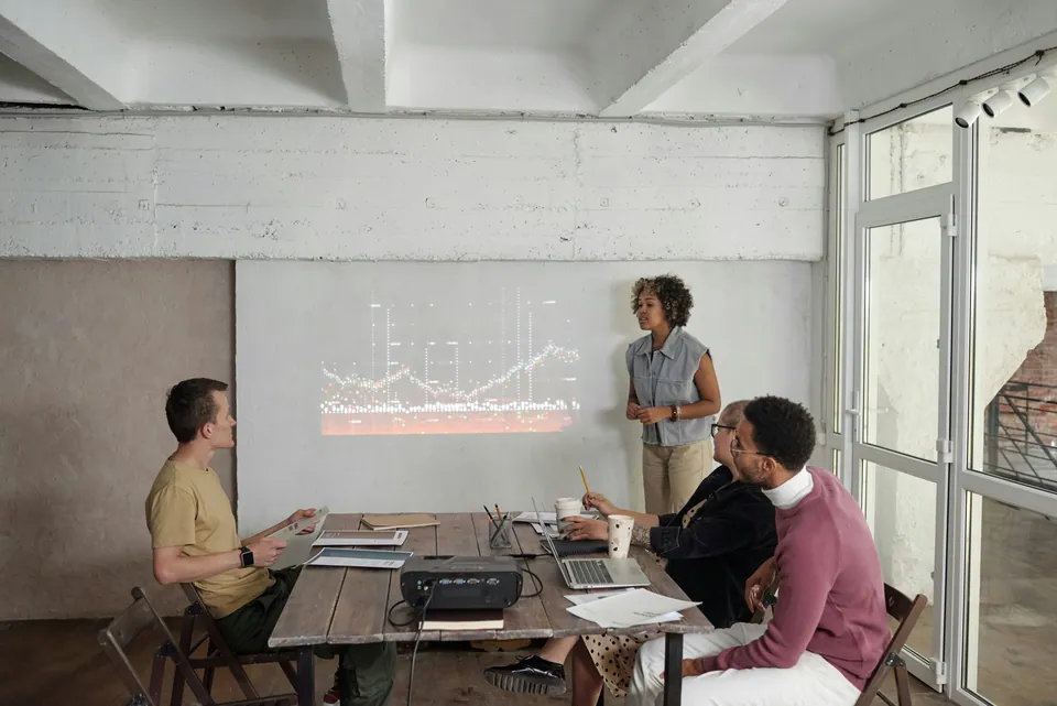 Woman presenting a chart on a projector screen to colleagues