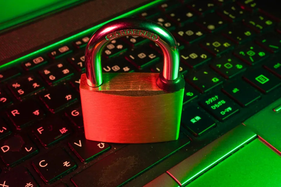 Red padlock resting on a green-lit laptop keyboard