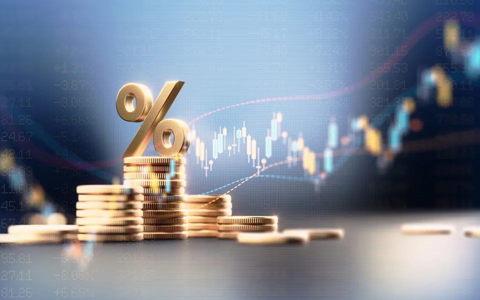 Gold percent sign on stacked coins in front of a price chart