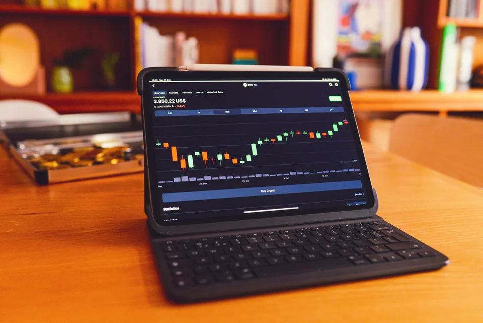 Tablet with a keyboard showing a candlestick chart on a wooden desk