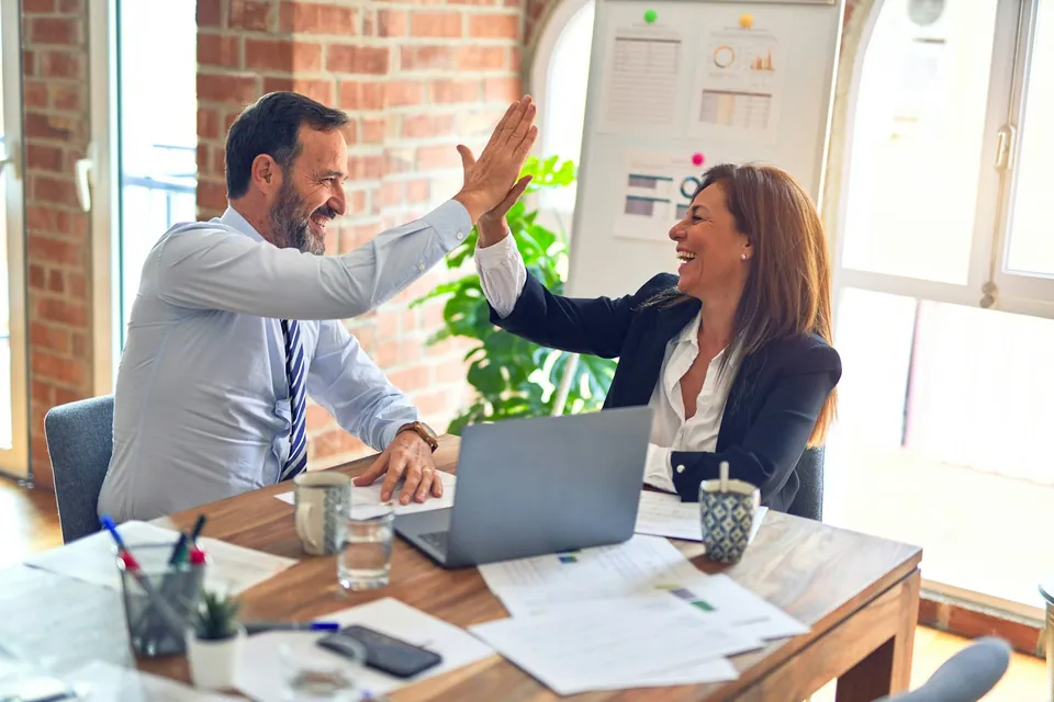Two colleagues giving a high five at a desk