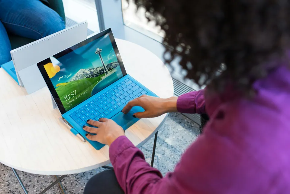 Person typing on a tablet with a blue keyboard at a cafe table