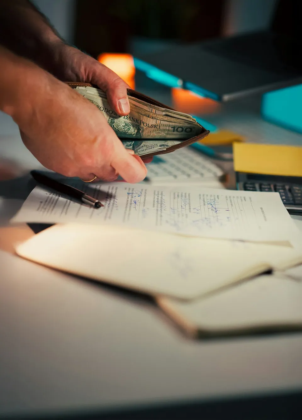 Hands counting cash over an open ledger notebook