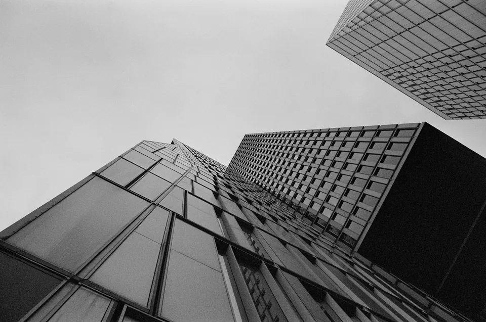 Looking up at dark glass office towers in black and white