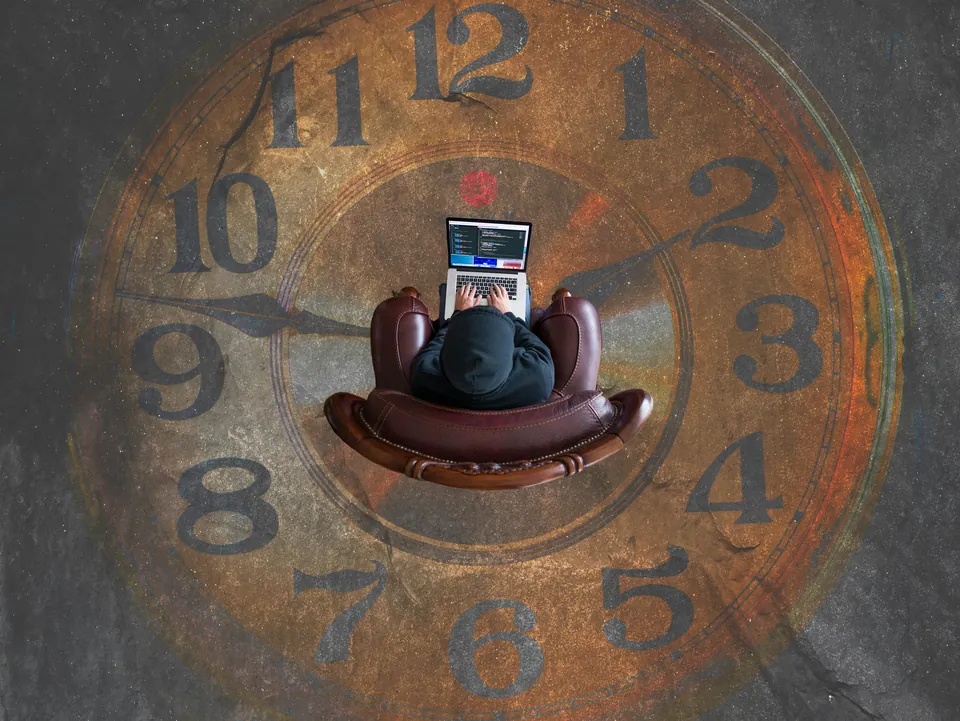 Overhead view of a person with a laptop on an armchair atop a giant clock face