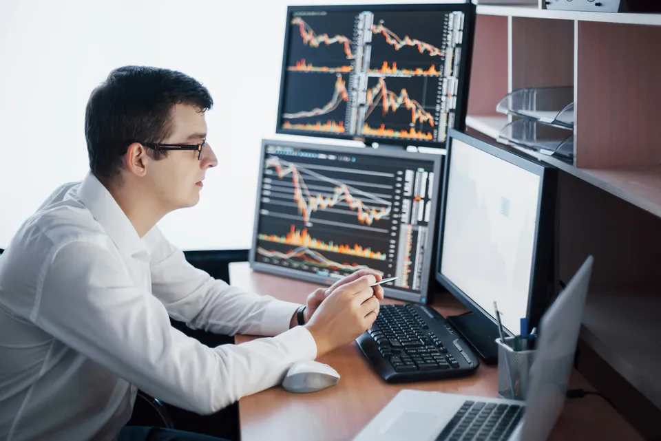 Young trader working at several chart monitors