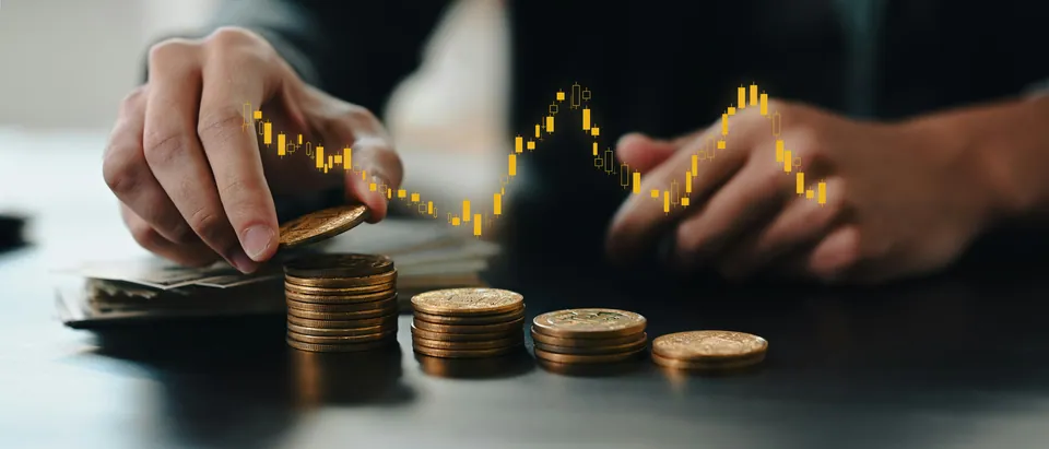 Hand stacking coins with a glowing price chart overlay