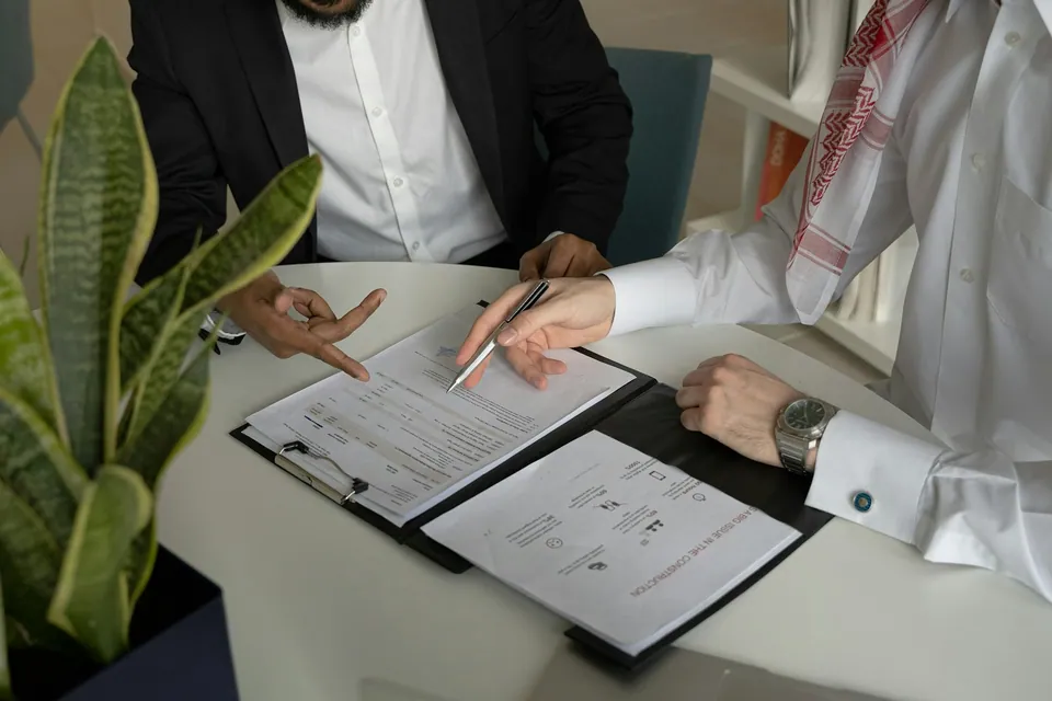 Two businessmen reviewing a contract on a clipboard