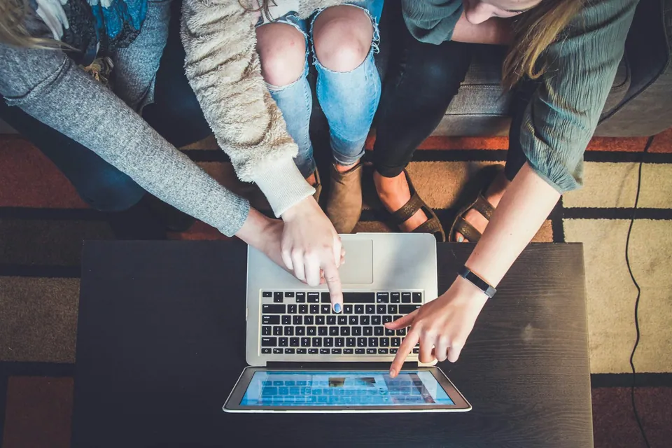 Friends pointing at a laptop screen together