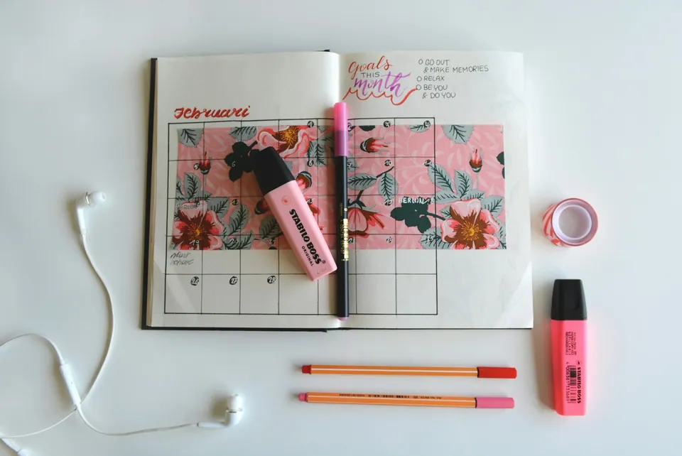 Open planner with a floral calendar, highlighters and earphones