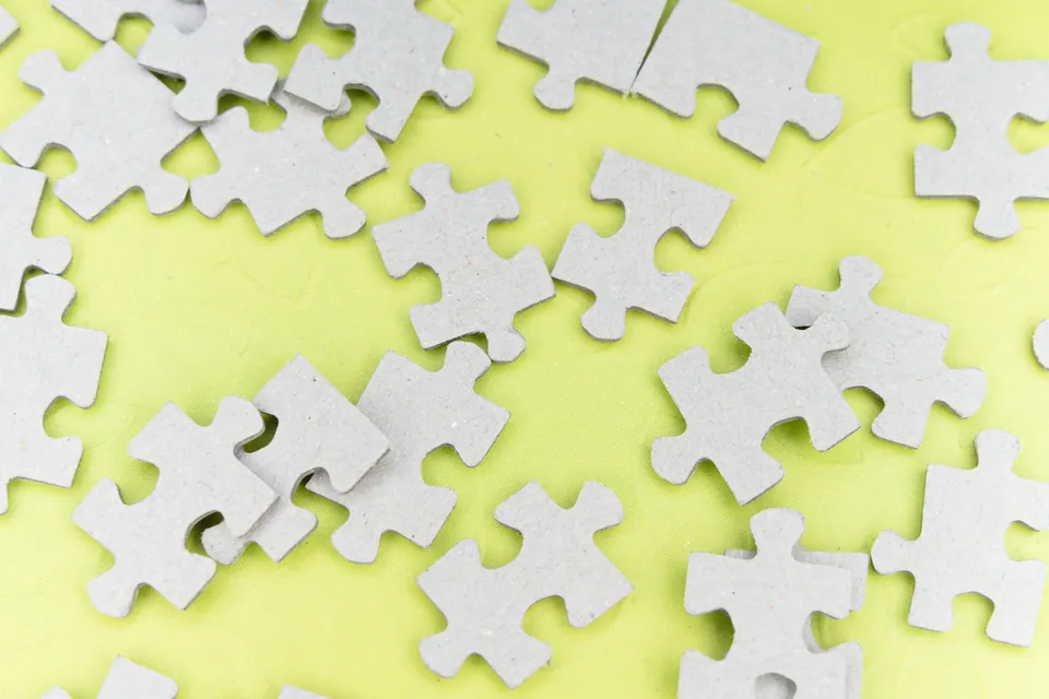 Scattered white puzzle pieces on a yellow background