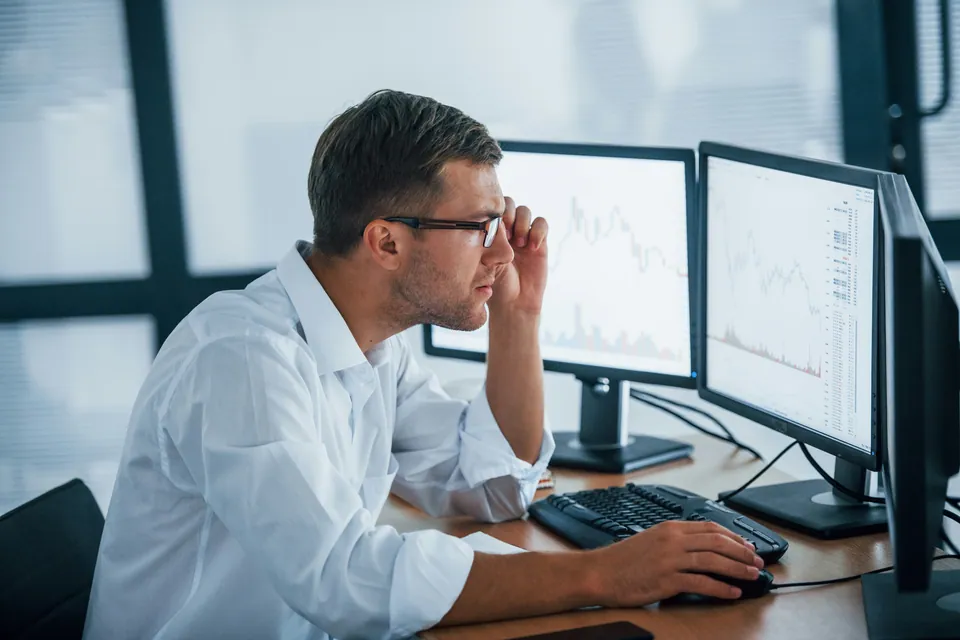 Young analyst studying charts on two monitors