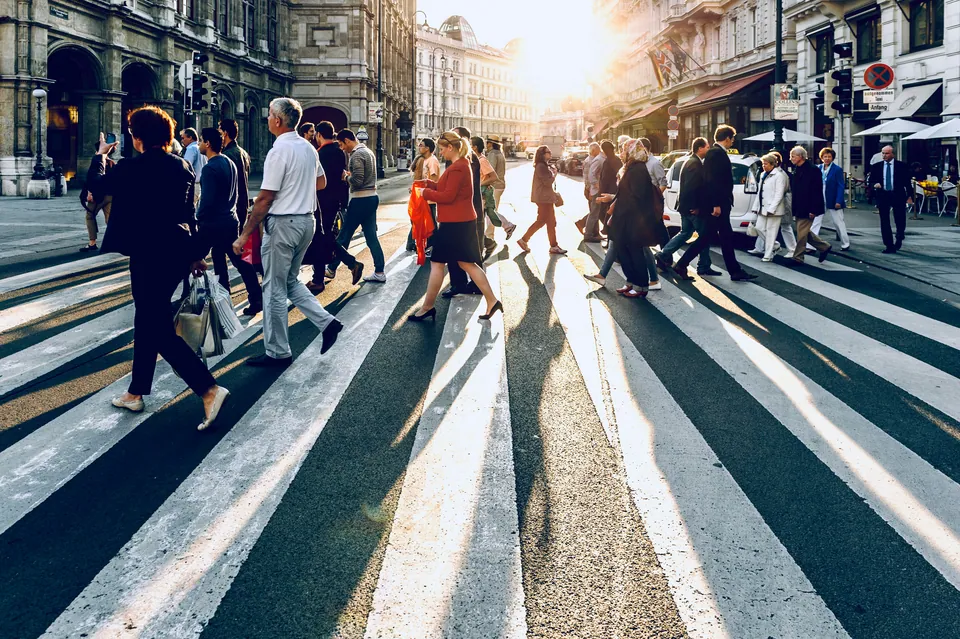 Crowd crossing a city street at a sunlit crosswalk