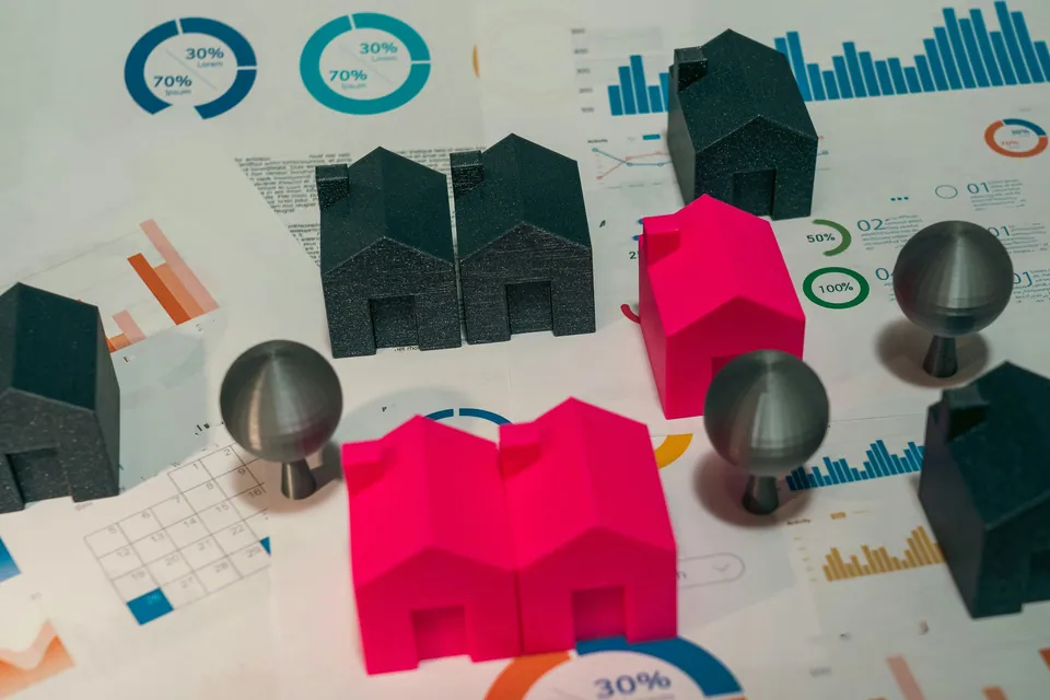 Model houses and metal pins on printed charts