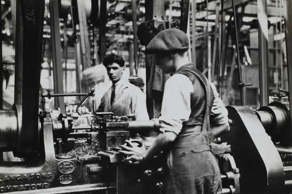 Black and white photo of workers at machines in an old factory