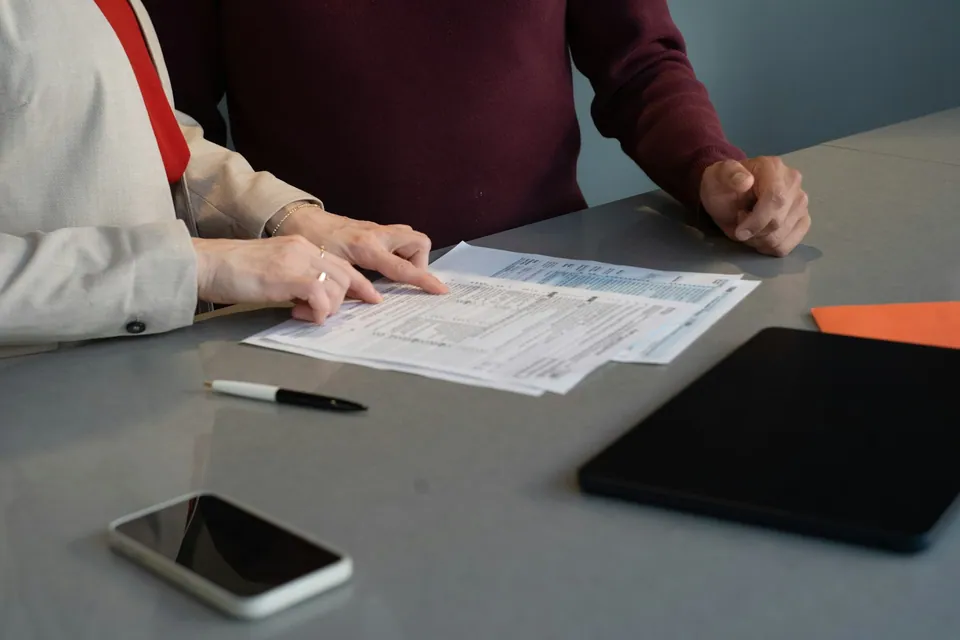 Two people reviewing a printed form at a gray table