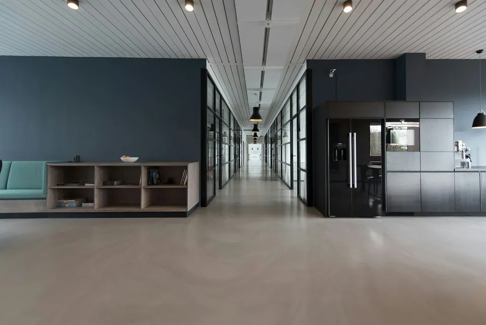 Empty modern office corridor with dark walls and a kitchenette