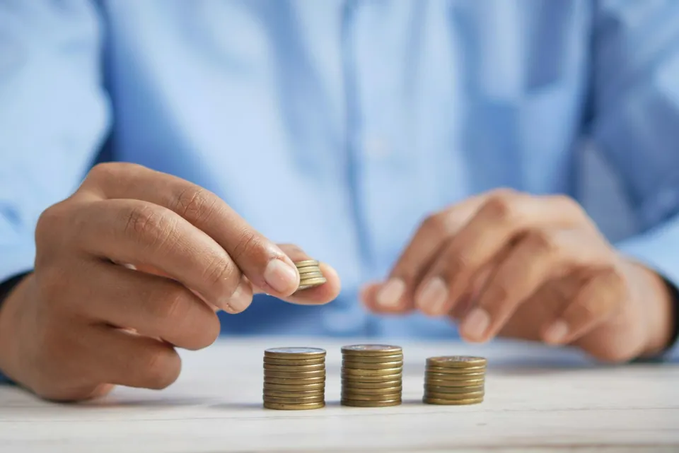 Hand stacking coins into small piles on a table