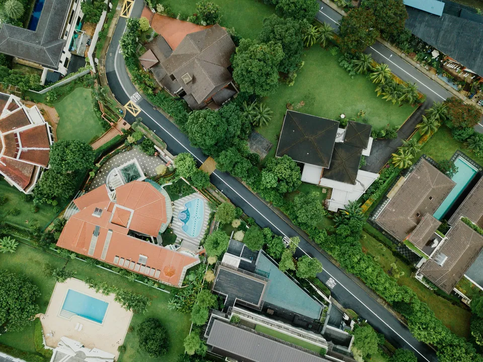 Aerial view of large homes with pools among trees
