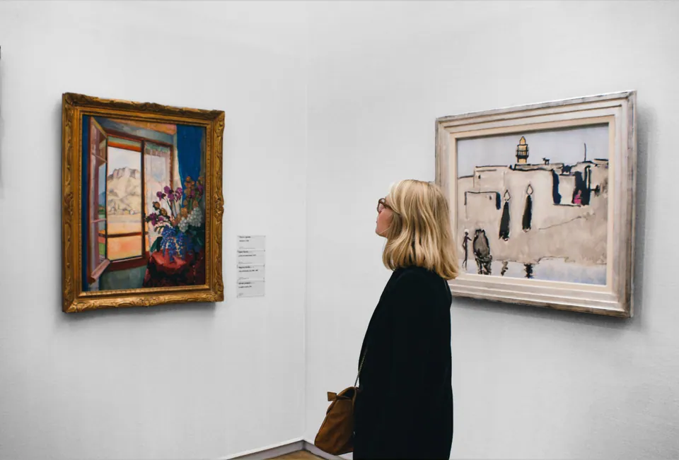 Woman looking at framed paintings in a gallery