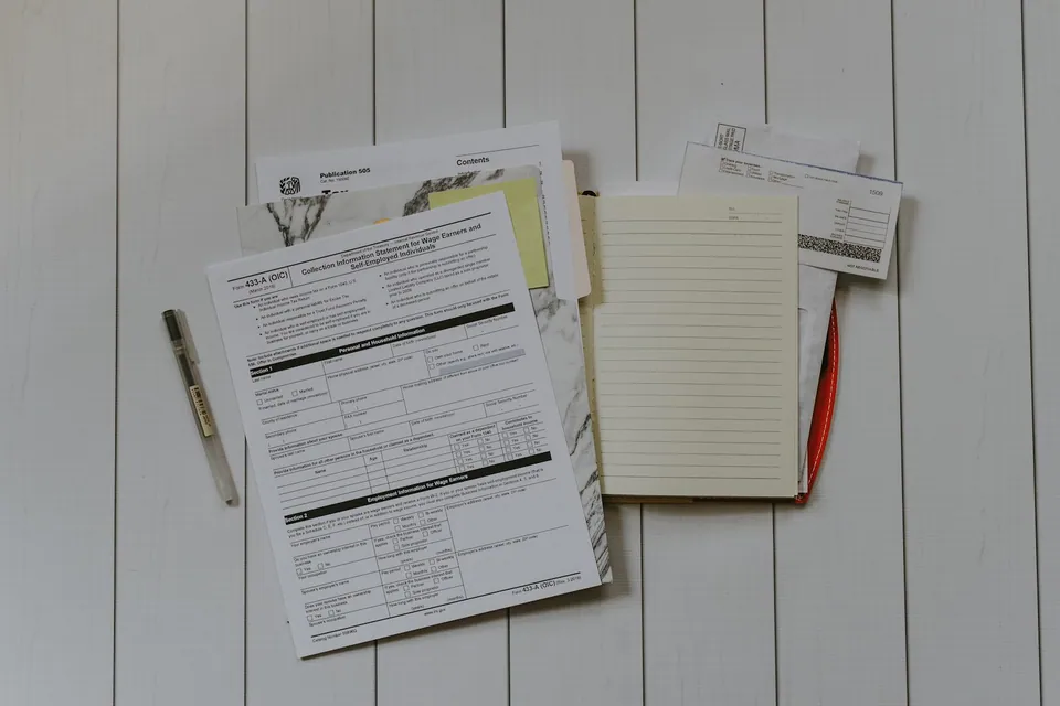 Tax forms, receipts and a notepad on a white wooden table