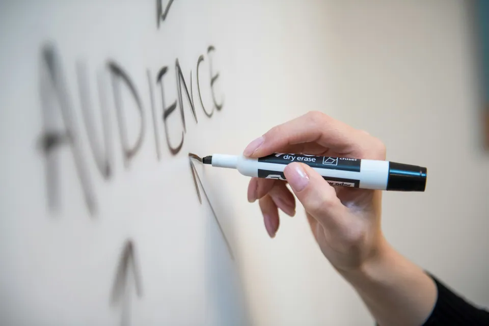 Hand writing the word AUDIENCE on a whiteboard