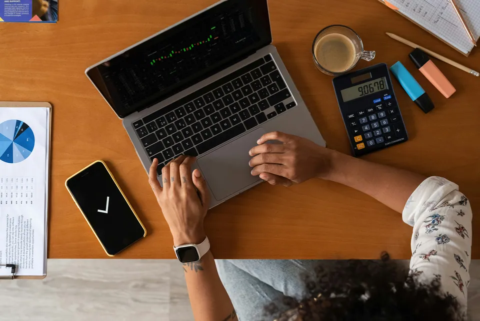 Overhead view of a person working on a laptop with a calculator and phone