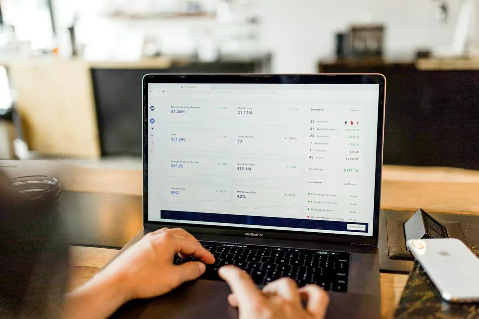 Hands typing on a laptop showing a portfolio dashboard